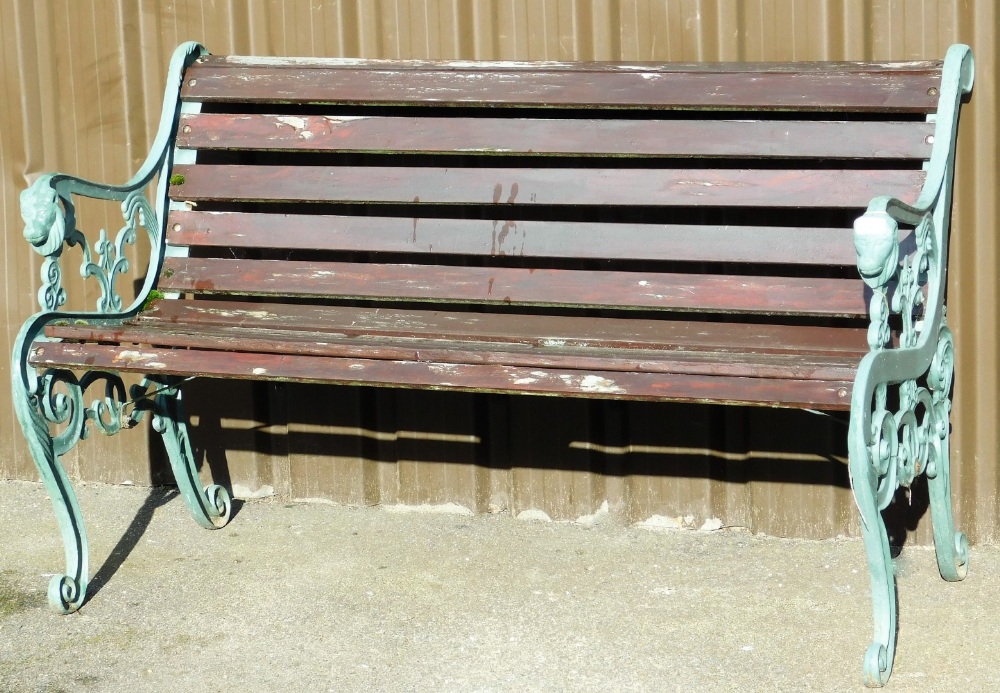 A cast iron and wooden slatted bench, the lion scroll supports painted green on wooden slats, 80cm h