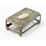 An Edward VII silver match box holder, with shell scroll detailed top on four bun feet, Birmingham 1