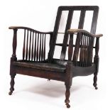 A 1920s oak framed lounge chair, on castors. (AF)