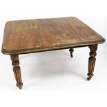 A Victorian mahogany extending dining table, on four baluster legs with castors, the canted corners,