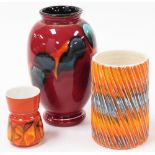 Three Poole pottery vases, to include a red Delphisware vase, 22cm high, an orange flared vase, 15cm