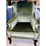 A wing back armchair, in green upholstery with mahogany splayed legs.