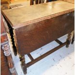 An oak drop leaf table with partial twist column supports.