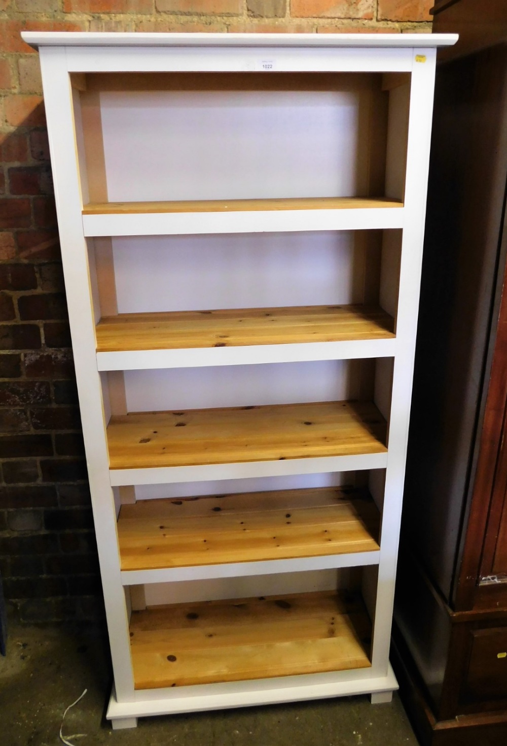 A white painted modern pine bookshelf, with five shelves.