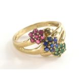 A 9ct gold dress ring, set with three layered design of flowers, with emeralds, rubies and