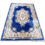 A Chinese wool cut carpet, with a design of flowers and leaves, on a navy blue ground with