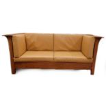 An oak Arts and Crafts sofa after a design by Gustav Stickley, with panelled sides and tanned