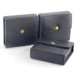 Three Coach black leather cases, with press stud openings, 11cm high, 11cm wide, 4cm deep.