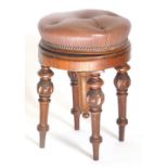 A Victorian walnut piano stool, with a brown studded leather revolving padded seat, on carved turned