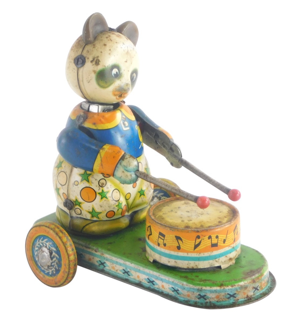 A mid 20thC tin plate wind up model toy of a panda playing a drum, 12cm high, 13cm wide.