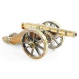 A model of an early 20thC cannon, in brass with a treen body, 36cm long.
