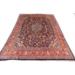 A Persian carpet, with a central medallion in pale blue surrounded by flower and leaf design, on