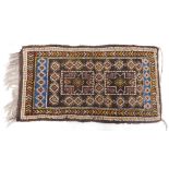A Turkoman style small rug, with a design of medallions on a brown ground with one wide, one