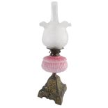 A Victorian cast iron oil lamp, with associated frosted shade, pink opaque moulded reservoir with