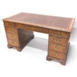 A walnut pedestal desk, the rectangular top with a brown gilt tooled leather inset, above nine