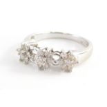 A 9ct white gold diamond dress ring, set with three diamond floral clusters and open work loop