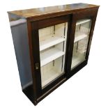 A stained pine bookcase, the sliding doors with recessed brass handles, enclosing adjustable shelves