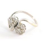 An 18ct white gold diamond twist ring, with two floral cluster diamond sections, on twist detailing,