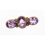 A Victorian 9ct gold amethyst bar brooch, set with three oval amethysts, each in a woven floral sett