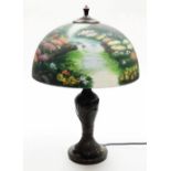 A Thomas Kinkade table lamp, the reverse decorated shade decorated with a meadow scene, on a cast me