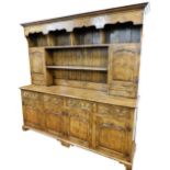 An oak and elm dresser, the plain moulded top with a carved under section and four open shelves, a f