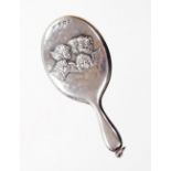 A George V silver hand mirror pendant, decorated with five embossed cherubs, with an oval mirror pla