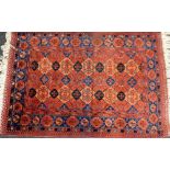 An Afghan red ground rug, decorated with floral medallions within a floral border, 160cm x 110cm.