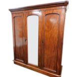 A Victorian mahogany triple wardrobe, with a central arched mirror door flanked by plain moulded pan