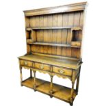 An oak dresser in 18thC style, the back with a moulded cornice above two shelves and two vacant rece
