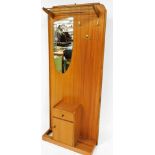 A retro teak hall stand, circa 1970s, with metal rails, shaped mirror and fixed pegs, above cupboard