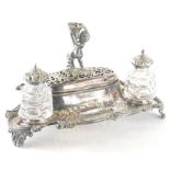 A 19thC silver plated ink stand, centred with a cherub with floral stem stand on a pierced lid and r