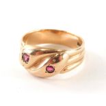 A 9ct gold dress ring, with two intertwined snakes heads, each set with ruby, on a three row rose go