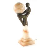 A 20thC Art Deco table lamp, formed as a dancing girl seated holding glass orb, on marble finish ste