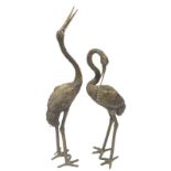 A pair of 20thC hollow metal garden stork ornaments, the first with neck raised, and another with ne