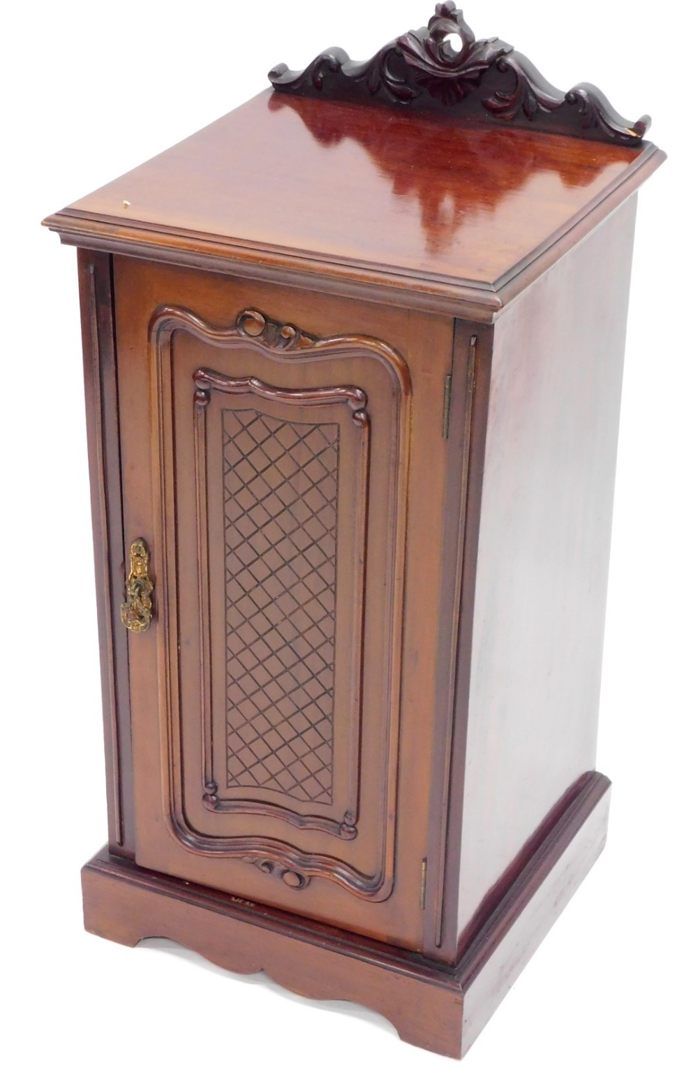 An Edwardian mahogany pot cupboard, with heavily carved cornice raised above lattice paneled door on