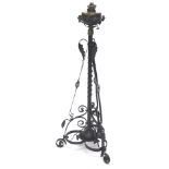 A late 19thC/early 20thC wrought iron floor lamp, with an oil lamp fitting and reservoir, the base d