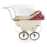 A 1930's vintage push-a-long doll's pram, in a white metal and material finish with red hood.