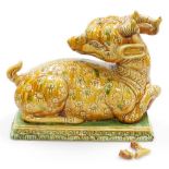 A Chinese salt glazed terracotta figure of a seated deer, with incised decoration, on a green glazed
