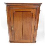 A George III oak and rosewood cross banded hanging corner cabinet, the dentil moulded pediment