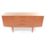 A mid century teak sideboard, with three central drawers, flanked by a pair of cupboard doors,