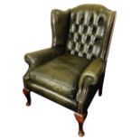 A green leather Chesterfield style wingback armchair, with button back and stud detailed arms, 100cm