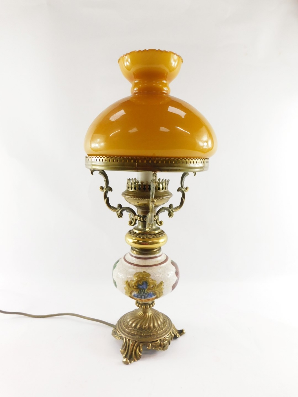 A 20thC oil lamp style electric table lamp, with orange glass shade on a brass three prong support,
