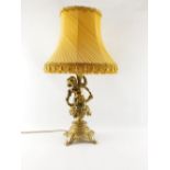 A continental brass cherub table lamp, the stem with putto holding a flower, on a floral seated base