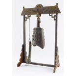 A Tibetan cast iron temple bell, on arched support, with bell and strike, 36cm high, 24cm wide, 12cm