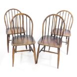 A set of four Ercol dark elm and beech Windsor dining chairs, raised on turned legs, united by an