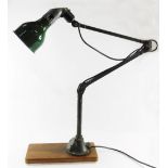 A 1920's Mek Elek anglepoise industrial lamp, with green shade and metal fittings, on a wooden base,