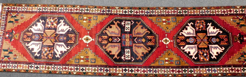 A Northern Persian red ground rug, decorated with geometric floral motifs, within repeating geometri