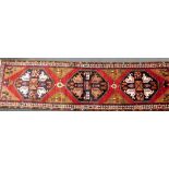 A Northern Persian red ground rug, decorated with geometric floral motifs, within repeating geometri