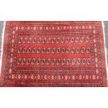 A Tekke Turkman red ground rug, decorated with three rows of fifteen guls, within repeating floral a