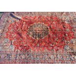 A Kashan red ground rug, decorated with a floral and arabesque design within repeating floral border